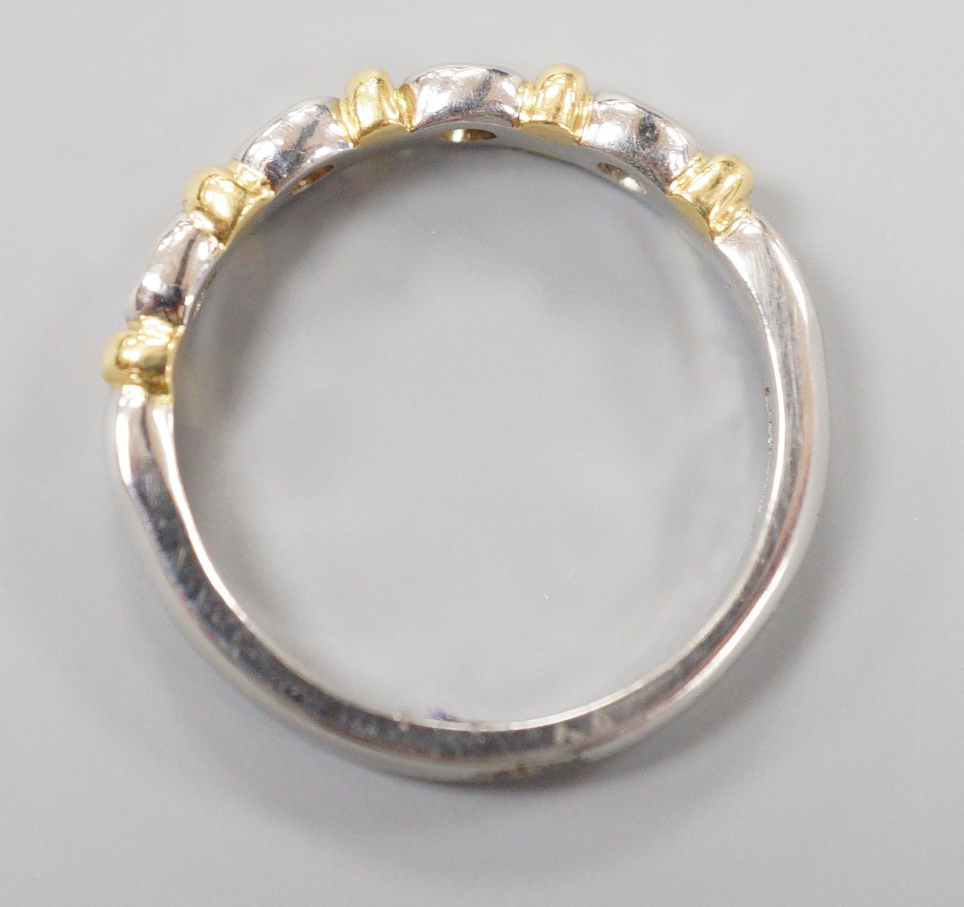 A modern platinum and yellow metal , four stone collet set diamond half hoop ring, size P, gross weight 6 grams
